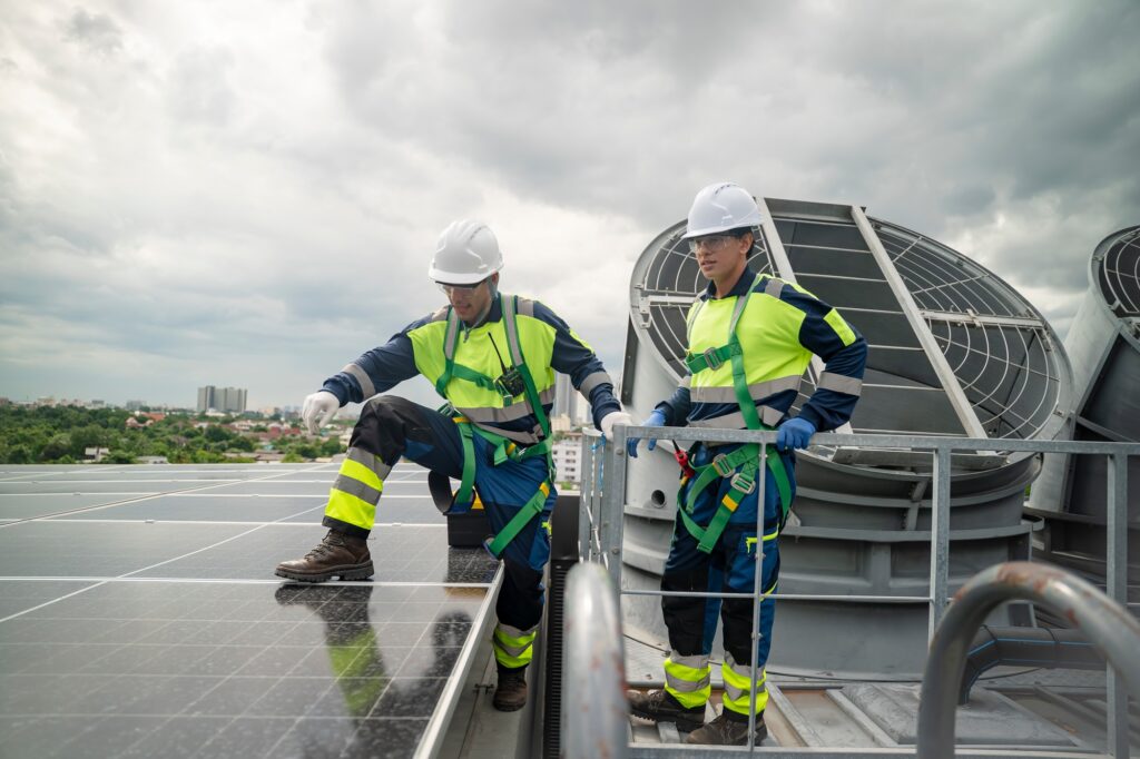 Workers install solar panels on a commercial rooftop in overcast weather